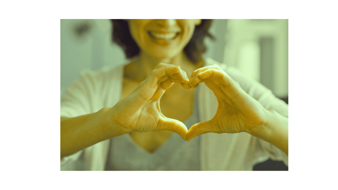 Frau formt mit den Händen ein Herz vor der Brust – Symbol für Herzenswunsch und inneres Anliegen